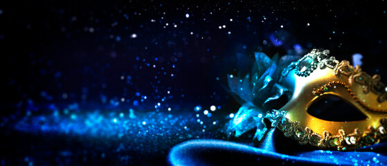 Beautiful carnival mask on black background with blue light and glitter, bokeh effect. Banner...