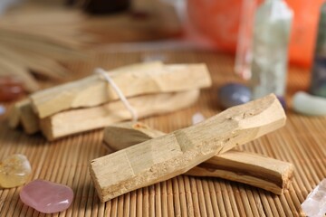 Palo santo sticks and gemstones on bamboo mat, closeup
