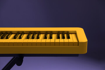 Yellow synthesizer on purple background, closeup. Electronic musical instrument