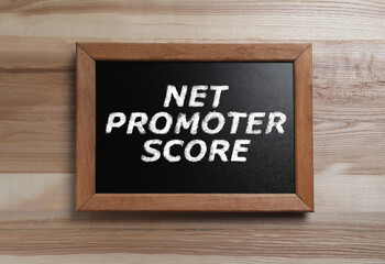 Chalkboard with Net Promoter Score (NPS) on wooden background. Customer satisfaction assessment