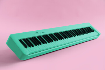 Cyan color synthesizer on pink background. Electronic musical instrument