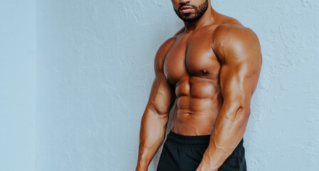 Naklejka premium Young strong man bodybuilder torso on white wall background