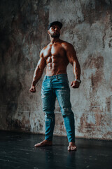 Fototapeta premium Young strong man bodybuilder on dark stone wall background