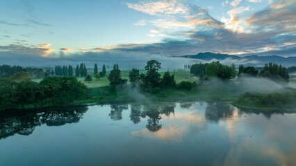 Misty morning over a tranquil Lake Aniwhenua. Birds reflect on the still water. Peaceful rural landscape.  MURUPARA, BAY OF PLENTY, NEW ZEALAND