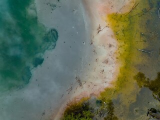 High-angle view of a colorful geothermal pool, showing vibrant green and yellow water, with mineral deposits. Nature's artistry. KUIRAU LAKE, ROTORUA, BAY OF PLENTY, NEW ZEALAND
