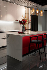Sleek kitchen interior features a white and red island with decorative flowers