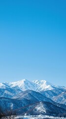 Fototapeta premium Snow-covered mountains tower majestically under a clear blue sky