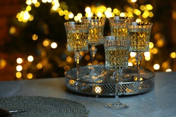 Tasty white wine in glasses on table against blurred lights. Bokeh effect