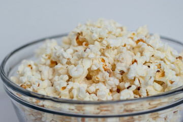 Close up of tasty popcorn in a glass bowl on white table background 