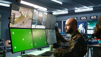 Army specialist working in war room operating surveillance tech, evaluating target data on green screen gear. Man doing job in base of operations, engaging enemy forces using mockup monitors, camera B