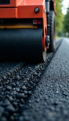 Close-up of asphalt paver blade spreading hot asphalt on a newly laid road surface, pavement laying, paving process, asphalt paver