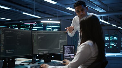 Engineering team colleagues in data center managing gear energy consumption, working on PC....