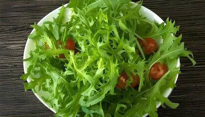 Fresh lactuca canadensis salad with cherry tomatoes in a white bowl on a wooden table. Perfect for healthy eating, vegetarian, or gastronomy concepts.