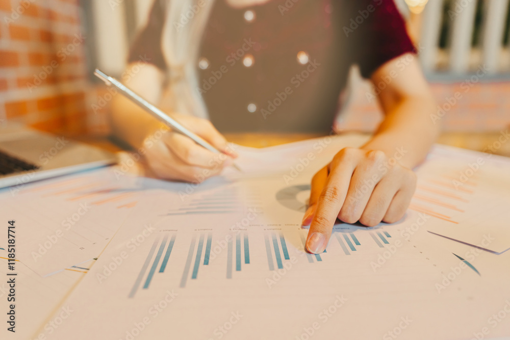 Poster focused analysis of business charts and graphs in modern workspace setting