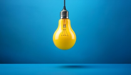 Bright Yellow Lightbulb Hanging Against a Blue Background
