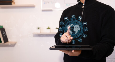 Logistics concept. Businessman manages his company from his tablet. Businessman touches hologram of planet Earth with icons about transportation and logistics