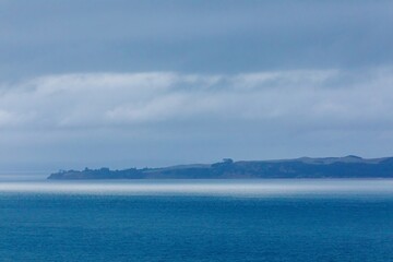 Tranquil coastal scene; overcast sky, calm ocean, low-lying land. Peaceful, muted colors. , TE KOROWAI-O-TE-TONGA PENINSULA, NORTHLAND, NEW ZEALAND