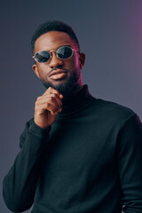 Stylish young man in black turtleneck and sunglasses posing confidently against a two tone background with a modern vibe