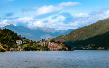 Fototapeta premium Lake Como offers a breathtaking view with colorful houses of Santa Maria Rezzonico nestled along the shore, backed by majestic mountains and a serene atmosphere, creating a picturesque scene in Lombar