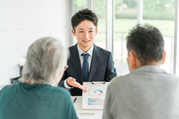 高齢者夫婦に説明・提案・案内・おすすめするビジネスマン（銀行員・資産運用・株・投資・保険） 