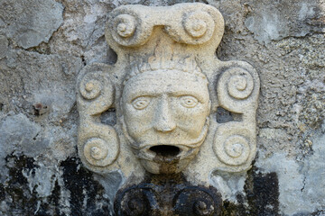 Water source with a human figure head expelling water looking like he is vomiting.