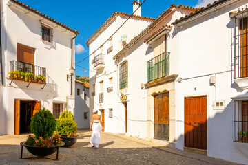 A young woman walks through the historic old town of the Andalusian White Village of Grazalema,...