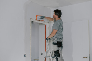 A young builder is plastering a doorway.