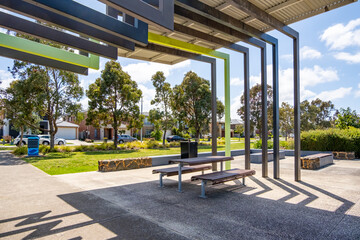 A covered shelter with a picnic table in a well-designed public space at a suburban neighborhood park in Australia, offering a recreational spot for outdoor activities and community enjoyment.