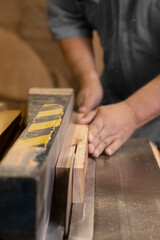 A male carpenter cutting wood with a circular saw in a carpentry sho