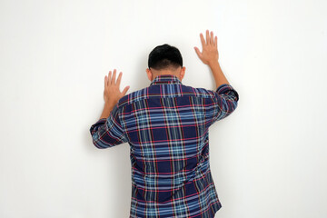 Back view of a man touching a wall showing lamenting fate gesture