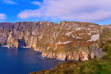 Slieve League in Donegal Ireland - the highest cliffs in Europe - Experience a breathtaking view of rugged cliffs merging with the calm ocean under a partly cloudy sky