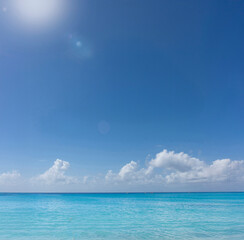 A tropical ocean scene with blue sky and clouds and sun n the distance .There is negative space in...