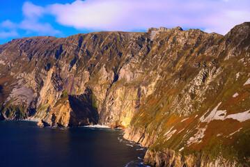 Slieve League in Donegal Ireland - the highest cliffs in Europe - Experience a breathtaking view of rugged cliffs merging with the calm ocean under a partly cloudy sky