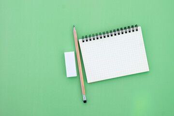 Blank Grid notebook open near pencil and eraser on green background.,writing, journaling, note-taking, planning,education concept.