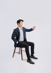 Full body image of young Asian business man sitting in chair on white background