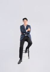 Full body image of young Asian business man sitting in chair on white background