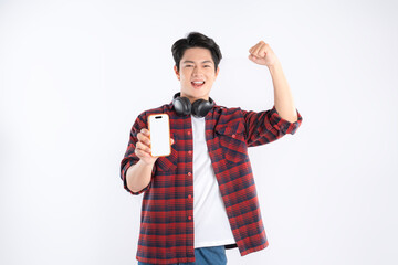 Portrait of dynamic Asian guy wearing headphones , using phone  and posing on white background