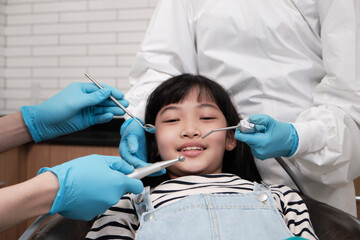 A cute Asian girl patient smiling at pediatric dental, teeth examined by dentist in treatment...