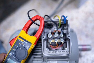 Electrical engineering uses a multimeter to measure the electrical current of wires motor.