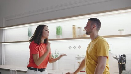 A couple argues in a modern kitchen, their expressions tense and voices raised. The scene captures the intensity of their disagreement in a sleek, contemporary setting.