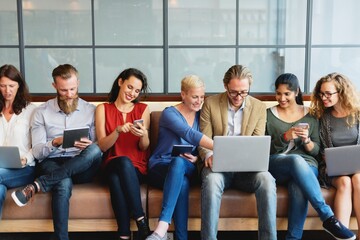 Group of diverse business people using devices. Business men and women with laptops and phones,...