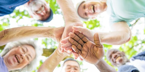 Diverse group of people joining hands in a circle, symbolizing unity and teamwork. Smiling faces, teamwork, and unity in a diverse group setting. People stacking hands, unity and teamwork.