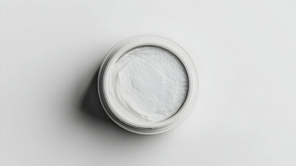 Top-down view of white cosmetic cream jar on white background.