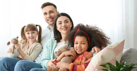 Happy couple with little adopted children at home