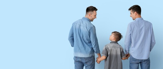 Happy gay couple and adopted child on light blue background with space for text