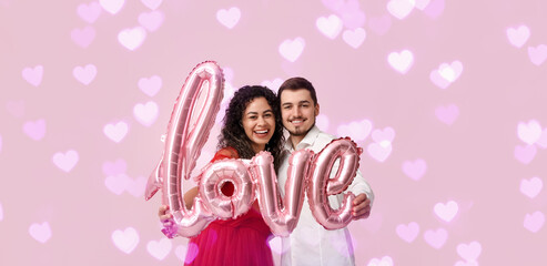 Young couple with air balloon in shape of word LOVE for Valentine's day on pink background
