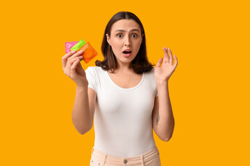 Beautiful shocked woman with condoms on yellow background. Safe sex concept