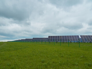 Solar panels in a field under a cloudy sky.  Clean energy source in a natural setting.