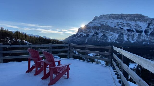 Slow Motion sunrise over viewpoint chairs overlooking Banff Canada Rocky Mountains .
