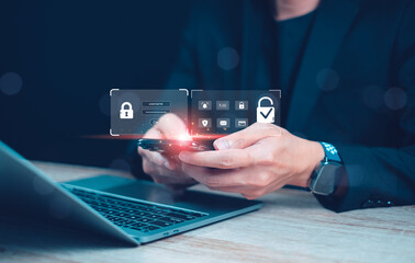 A person interacting with a smartphone displaying security features, with a laptop nearby, suggesting digital security and technology themes.